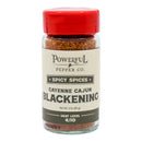 A glass jar of Powerful Pepper Company’s Cajun Blackening Seasoning features a red lid and a “Spicy Spices” label, with a moderate heat level of 4 out of 10. Inspired by the classic Cajun blackened recipes popularized by Chef Paul Prudhomme, this blend infuses bold flavor into any dish.