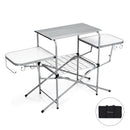 The DirectDeals Foldable Outdoor BBQ Table Grilling Stand features a metal frame, two white side tables, hooks, wire shelf below, and comes with a zippered black carrying bag.