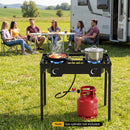 An outdoor scene shows the DirectDeals 2 Burner Propane Stove 160000 BTU with Adjustable Regulator cooking food, a red gas cylinder below, and five people by an RV table. Note: Gas cylinder not included.