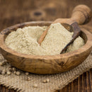 A wooden bowl filled with The Spice Lab Ground White Pepper, a light beige seasoning from The Spice Lab popular in bulk foodservice spices, with a small wooden scoop resting inside, placed on a burlap cloth alongside whole peppercorns.