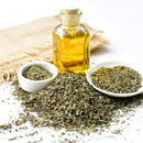 An aromatic pile of The Spice Lab Organic Sweet Basil, two small bowls of herbs, and a cork-topped glass bottle of oil are artfully arranged on a white surface beside a piece of burlap—ideal for Italian-inspired dishes.