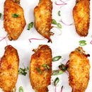 Six crispy chicken wings arranged on a white surface, garnished with sliced green onions and thin strips of pink radish, perfectly coated in The Spice Lab Best Seller Seasoning Set by The Spice Lab for an extra kick of flavor.