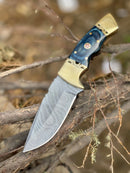 The Texan Knives Hunting Knife features a 9" forged Damascus steel blade, Pakka wood handle with brass bolster, and comes with a leather sheath—a striking addition to any outdoor collection.