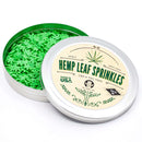 An open round tin labeled “The Spice Lab Hemp Leaf Sprinkles CBD & THC Free” displays green, leaf-shaped sprinkles inside. Made in the USA and free of CBD and THC, these edible decorations from The Spice Lab are perfect for parties.