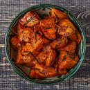 A bowl of roasted sweet potatoes with herbs and seasoning, finished with a sprinkle of The Spice Lab Organic Spanish Sweet Paprika, sits on a dark wooden table. The golden-brown sweet potatoes are dotted with pieces of rosemary, their flavor elevated by the subtle smokiness of The Spice Lab’s Organic Spanish Sweet Paprika.