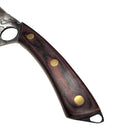 Close-up of a Spaceman Knives Meteor Series Mega Chef handle, crafted from dark wood with three brass rivets, resting on marble beside a black cloth.