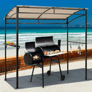 A black grill cooks food under the DirectDeals 7 x 4.5 Feet Grill Gazebo Outdoor Patio Garden BBQ Canopy Shelter-Brown on a beachside patio, with a brick wall behind and ocean views beyond.