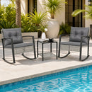 The 3-Piece Outdoor Rocking Chair Set with Coffee Table - Gray by DirectDeals sits on a poolside patio, surrounded by green plants and a large decorative white pot.