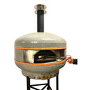 The WPPO Professional Lava Digital Controlled Wood-Fired Oven With Convection Fan by WPPO LLC Direct, featuring a gray tiled, dome-shaped design crafted from volcanic stone with orange accent tiles and a vertical chimney, stands on a metal base against a white background. A person’s hand uses metal tongs to place a piece of wood into the oven’s mouth.