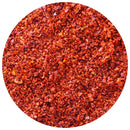 Close-up of The Spice Lab Aleppo Pepper Chili Flakes by The Spice Lab, displaying vibrant red and orange flakes with seeds and diverse textures, artfully arranged in a circular frame on a white background. This blend is celebrated for its mild heat and rich, aromatic flavor.
