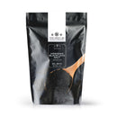 A 1 lb resealable black bag labeled The Spice Lab Hawaiian Black Lava Salt Medium Grain features The Spice Lab branding and an image of a wooden spoon filled with black salt on the front. This medium grain finishing salt is ideal for adding bold flavor and striking visual appeal to your dishes.