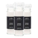 Three clear jars from The Spice Lab Spanish Sea Salt Coarse Grain with Grinder 3-Pack, each featuring coarse sea salt crystals, black labels, and transparent ceramic grinder tops, are arranged side by side against a white background.