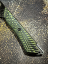 Close-up of the Spaceman Knives Gravity Series Chef Knife handle, featuring a textured green and black zigzag pattern, visible screw, and metal loop, set on a speckled dark surface.