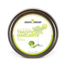 Round tin labeled The Spice Lab Traditional Margarita Salt Cocktail Rimmer by The Spice Lab, featuring an image of a margarita glass, a lime wedge, and a lime half on the white and green front. This premium salt is perfect for rimming cocktail glasses to enhance your favorite drinks. Net weight: 3.5 oz (99g).
