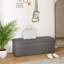 A gray upholstered bench with a white handbag sits against the wall, matching the cozy, modern feel of DirectDeals 5 Pieces Patio Rattan Furniture with 2 Ottomans and Tempered Glass Coffee Table-Red in the outdoor space.