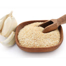 A wooden bowl filled with The Spice Lab Minced Garlic 1 lb Bulk Foodservice Spice and a wooden scoop, displayed alongside a head of garlic and some separated garlic cloves on a white background—ideal for anyone seeking bulk minced garlic or premium seasoning from The Spice Lab for their recipes.