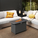 A modern outdoor patio with cushioned sofas, yellow pillows, the DirectDeals 44.5 Inch Propane Fire Pit Table Rattan Gas 2-in-1 with Stainless Steel Burner, lanterns with candles, lush plants, and a textured brown rug.