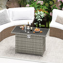 A wicker outdoor table with drinks, fruit, and glasses sits beside the DirectDeals 44.5 Inch Propane Fire Pit Table Rattan Gas 2-in-1 with Stainless Steel Burner, surrounded by curved white cushioned sofas on a patio rug with plants nearby.