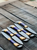 The Texan Knives Best Japanese Knife Set features a 13" forged stainless steel chef knife with an olivewood and epoxy resin handle, plus a leather sheath, displayed in a fan shape on rustic wood.