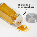 A spice jar from The Spice Lab 12 Pack Empty French Glass Spice Jars lies tipped over, spilling yellow powder with its stainless-steel lid off to the side. Text and an arrow highlight the jar’s shaker and pour spout cap, demonstrating practical seasoning storage using these empty French glass spice jars from The Spice Lab.