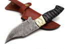 The Texan Knives Custom Handmade Damascus Skinning Knife features a patterned steel blade, resin and brass handle, and a brown leather sheath with stitched detailing and snap button closure.