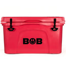 Introducing the Bob The Cooler Co. 50 QT/47.3L Hard Cooler - El Amigo by Bob - The Cooler Co.: This vibrant red cooler features sturdy black latches and the word "BOB" in bold black letters on the front, with a playful O that includes a smiley face and two lightning bolts. Inspired by the classic El Amigo 50qt design, it boasts extra-thick insulated walls for superior cold retention and includes a removable dry basket for added convenience.