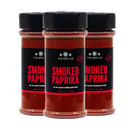 Three containers of The Spice Lab Smoked Spanish Paprika Powder, each 4.1 oz with black lids and red labels, are arranged in a row on a white background—an ideal choice for BBQ seasoning or adding authentic smoked Spanish paprika flavor.