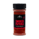 A clear plastic jar of The Spice Lab Smoked Spanish Paprika Powder with a black lid and label, containing 4.1 oz (116g) of vibrant red smoked Spanish paprika. The label describes it as an all-around multipurpose spice, ideal for adding rich flavor to your favorite dishes and BBQ seasoning blends.