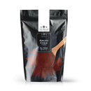 A 1 lb resealable black bag from The Spice Lab, labeled “The Spice Lab Ancho Chile Powder,” features a wooden spoon filled with red chili powder on the front. Ideal for BBQ rubs or as a bulk foodservice spice.