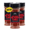 Three jars of The Spice Lab Double Crushed Red Pepper Flakes are displayed, one featuring a yellow NEW! label. Each jar has a black lid and showcases bold red and white text on stylish black labels, accentuating the finely crushed pepper flakes from The Spice Lab, celebrated for their balanced heat.