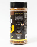 A Chiles and Smoke Canyon Crust Beef Seasoning bottle labeled "In Crust We Trust" features text describing it as the ultimate BBQ rub for beef, ideal for steak, brisket, burgers, and ribs. The container includes ingredient details, a chef’s endorsement, and a US flag to indicate it’s made in the USA.