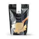 A black resealable bag labeled The Spice Lab Granulated Honey from The Spice Lab features a wooden spoon brimming with light yellow granulated honey spilling onto the front, emphasizing its versatility for baking or adding a hint of sweetness to BBQ rubs.