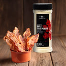 A small orange bowl filled with crispy bacon sits next to a jar of The Spice Lab Maple Sugar Powder by The Spice Lab, a flavorful sweetener crafted from pure maple syrup powder, on a wooden surface.