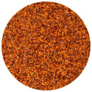 Close-up view of a circular pile of The Spice Lab Double Crushed Red Pepper Flakes, featuring small, uneven pieces in vibrant shades of red and orange. These flakes from The Spice Lab offer balanced heat and texture that highlight their bold flavor.