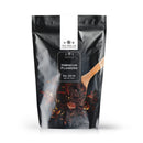 A resealable black bag labeled The Spice Lab Whole Hibiscus Flowers is displayed, showcasing premium whole hibiscus flowers as a versatile botanical ingredient for foodservice; a wooden spoon scoops the dried hibiscus flowers against a white background.