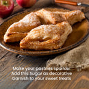 Two sugar-dusted pastries rest on a rustic plate, with whole apples and a knife nearby. Text on the image highlights Sanding Con AA Sugar from The Spice Lab as the perfect sparkling garnish for sweet treats—a must-have for anyone passionate about decorative baking.