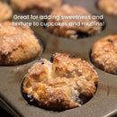 Close-up of freshly baked muffins in a muffin tin, topped with The Spice Lab Sanding Con AA Sugar. White text over the image reads, Great for adding sweetness and texture to cupcakes and muffins! Perfect for decorative baking.