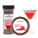 A container and tin of The Spice Lab Tropical Hibiscus Sugar Cocktail Rimmer are displayed next to a cocktail glass rimmed with the vibrant sugar and filled with a bright pink drink, perfect for Cosmopolitans. The packaging from The Spice Lab features an elegant hibiscus flower design.