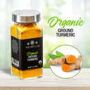 A glass jar of The Spice Lab Organic Ground Turmeric rests on a wooden surface, capturing the spirit of authentic Indian cuisine. Beside it lies an image of fresh turmeric roots, some sliced to reveal their vivid orange core, emphasizing the natural vibrancy and purity found in The Spice Lab’s ground turmeric powder.