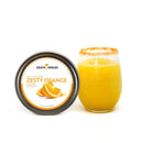 A round container of The Spice Lab Zesty Orange Sugar Cocktail Rimmer by The Spice Lab sits beside a glass of orange drink with a sugared rim, highlighting the ideal orange cocktail rimming sugar. Both are displayed on a white background.