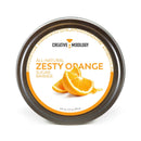 A round tin labeled The Spice Lab Zesty Orange Sugar Cocktail Rimmer features an orange-slice design in the center with orange and white text. This 3.5 oz (99 g) tin holds all-natural orange cocktail rimming sugar from The Spice Lab, ideal for adding a burst of citrus flavor as a margarita rimmer or as a vibrant garnish for cocktails.