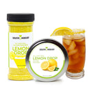 A container and tin of The Spice Lab Lemon Drop Sugar Cocktail Rimmer by The Spice Lab are placed beside a glass of iced tea with a sugared rim and a lemon wedge, making it ideal for giving Citrus Cocktails a zesty finish. The packaging highlights yellow sugar crystals and displays images of lemons.