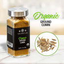 A glass jar of The Spice Lab Organic Ground Cumin, topped with a metal lid, rests on the counter. Nearby are cumin seeds and text that reads: “Organic Ground Cumin—ideal for infusing rich flavor into curries or crafting your own BBQ rubs.”.