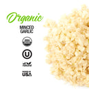 A pile of The Spice Lab Organic Minced Garlic sits beside labels highlighting USDA Organic, Kosher certification, All Natural, and Packed in USA. The text features “Organic Minced Garlic” in green and black lettering—perfect for adding bold flavor to your favorite dishes like avocado toast.
