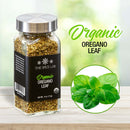 A glass jar of The Spice Lab Organic Oregano Leaf rests on a wooden surface, featuring a close-up image of fresh oregano leaves and the product name in green and black lettering against a blurred nature background—ideal for enhancing your Italian recipes or bringing authentic Mediterranean flavors to any dish.