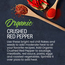 Wooden spoons display The Spice Lab Organic Crushed Red Pepper Flakes and chili powder, ideal for Italian cuisine. Whole red chili peppers are arranged above. Descriptive text highlights The Spice Lab’s organic crushed red pepper as a flavorful pizza seasoning for pasta, eggs, and vegetables, all set against a dark background.