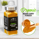 A glass jar labeled The Spice Lab Organic Indian Curry Powder rests on a counter. Beside it, The Spice Lab curry seasoning is displayed in a wooden bowl with a scoop. Text reads The Spice Lab Organic Indian Curry Powder.