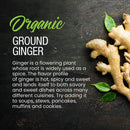 A fresh ginger root with green leaves rests on a dark textured surface next to text highlighting the warm, aromatic flavor and versatility of The Spice Lab Organic Ground Ginger by The Spice Lab—a popular baking spice enjoyed in a variety of dishes.