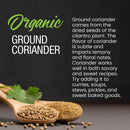 A wooden spoon with The Spice Lab Organic Ground Coriander and coriander seeds, a cilantro leaf, and text describing The Spice Lab Organic Ground Coriander’s flavor and uses in spice blends and Indian cooking on a dark surface.