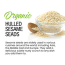A glass bowl and wooden spoon filled with The Spice Lab Organic Hulled Sesame Seeds. Text highlights their distinctive nutty flavor and notes their wide use around the world in stir-fries, baking, and other culinary creations.